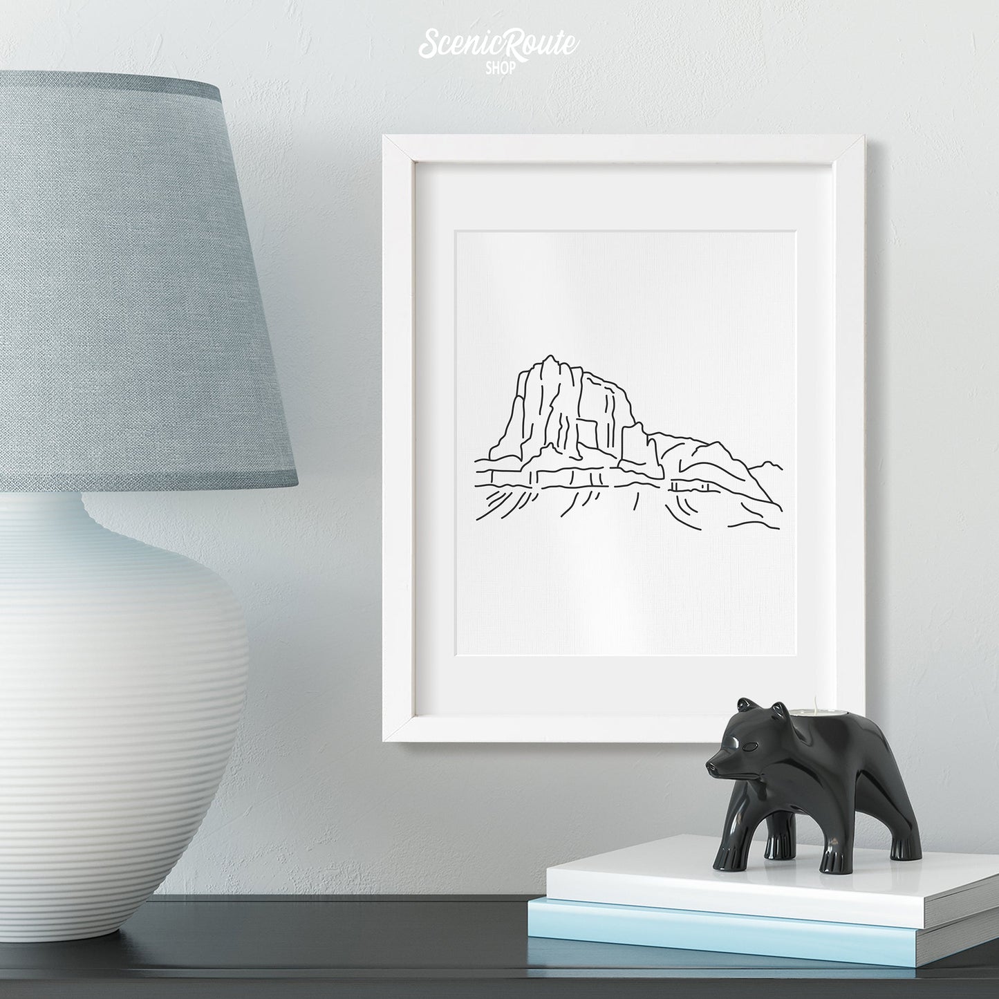 A framed line art drawing of Guadalupe National Park above a table with a lamp and figurine