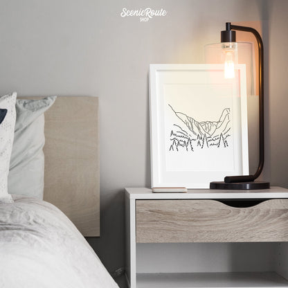 A framed line art drawing of Kings Canyon National Park above a nightstand next to a bed