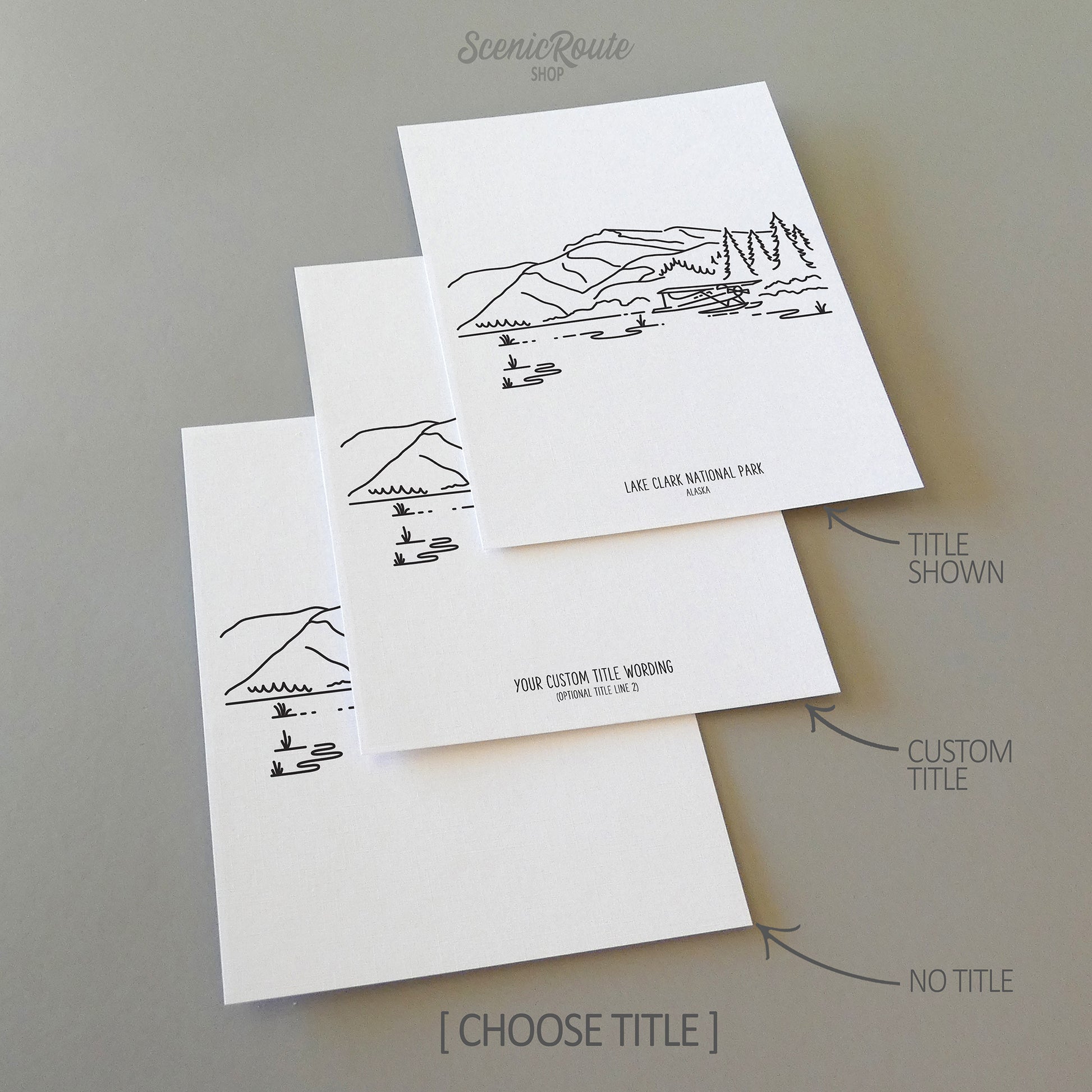 Three line art drawings of Lake Clark National Park on white linen paper with a gray background. The pieces are shown with title options that can be chosen and personalized.