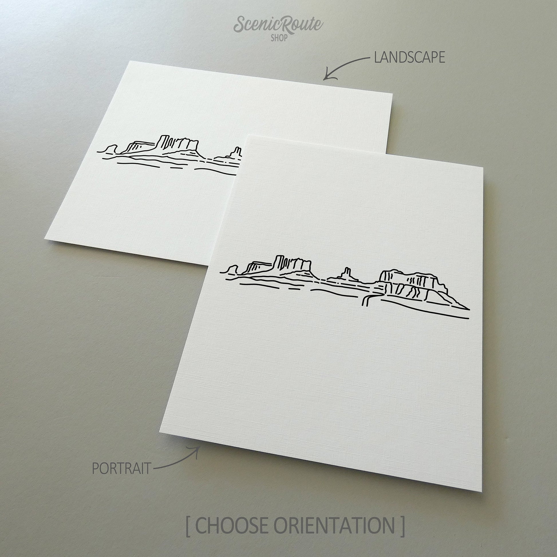 Two line art drawings of Monument Valley on white linen paper with a gray background.  The pieces are shown in portrait and landscape orientation for the available art print options.