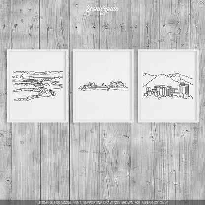 A group of three framed drawings on a wood wall. The line art drawings include Canyonlands National Park, Monument Valley, and the Salt Lake City Skyline