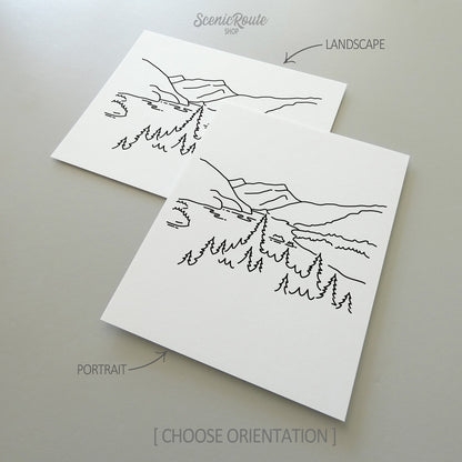 Two line art drawings of North Cascades National Park on white linen paper with a gray background.  The pieces are shown in portrait and landscape orientation for the available art print options.