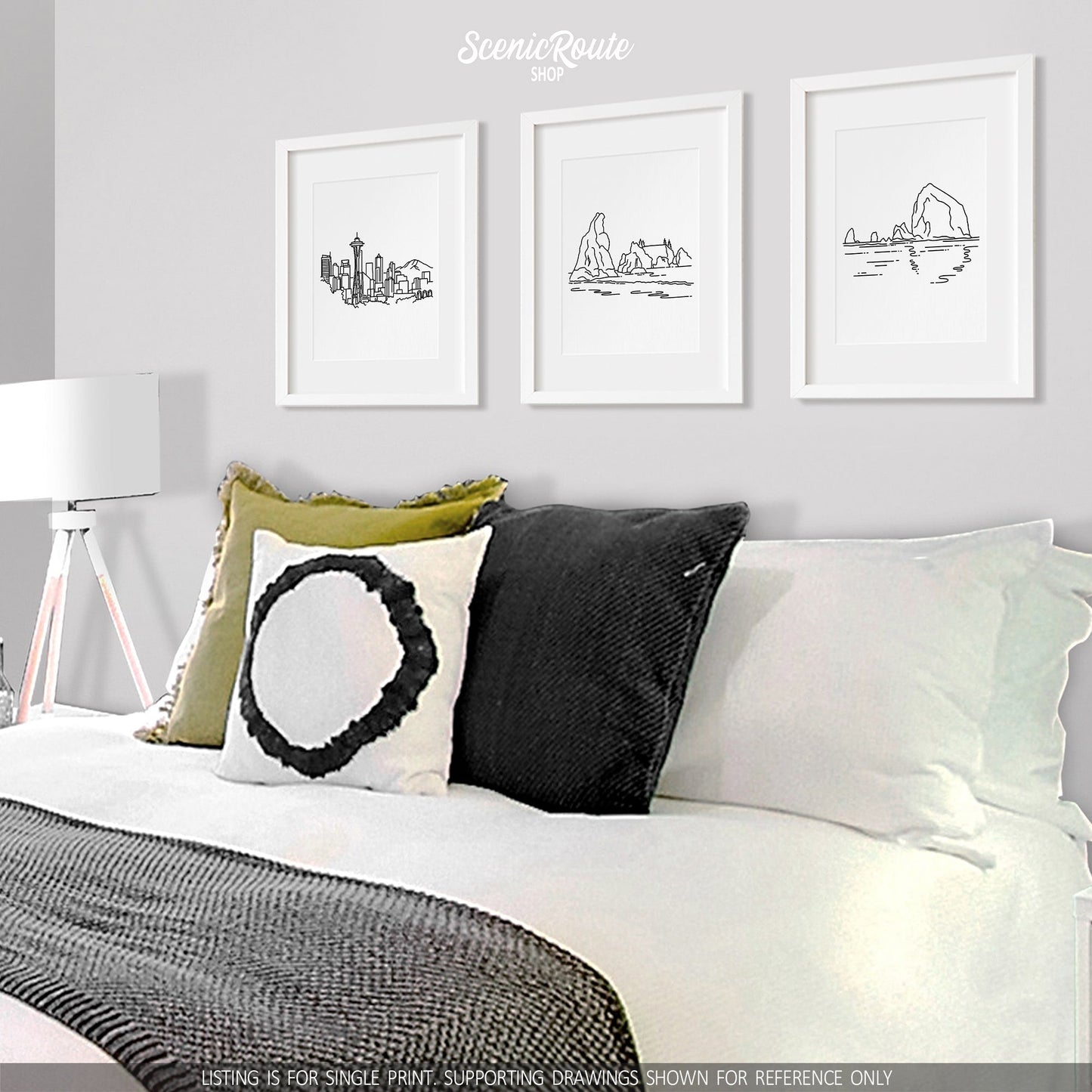 A group of three framed drawings on a white wall above a bed. The line art drawings include the Seattle Skyline, Olympic National Park, and Haystack Rock