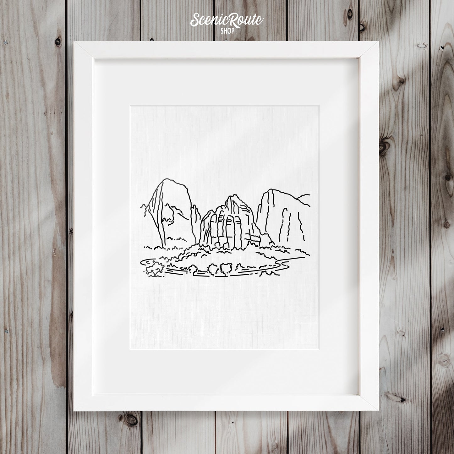 A framed line art drawing of Zion National Park on a wood wall