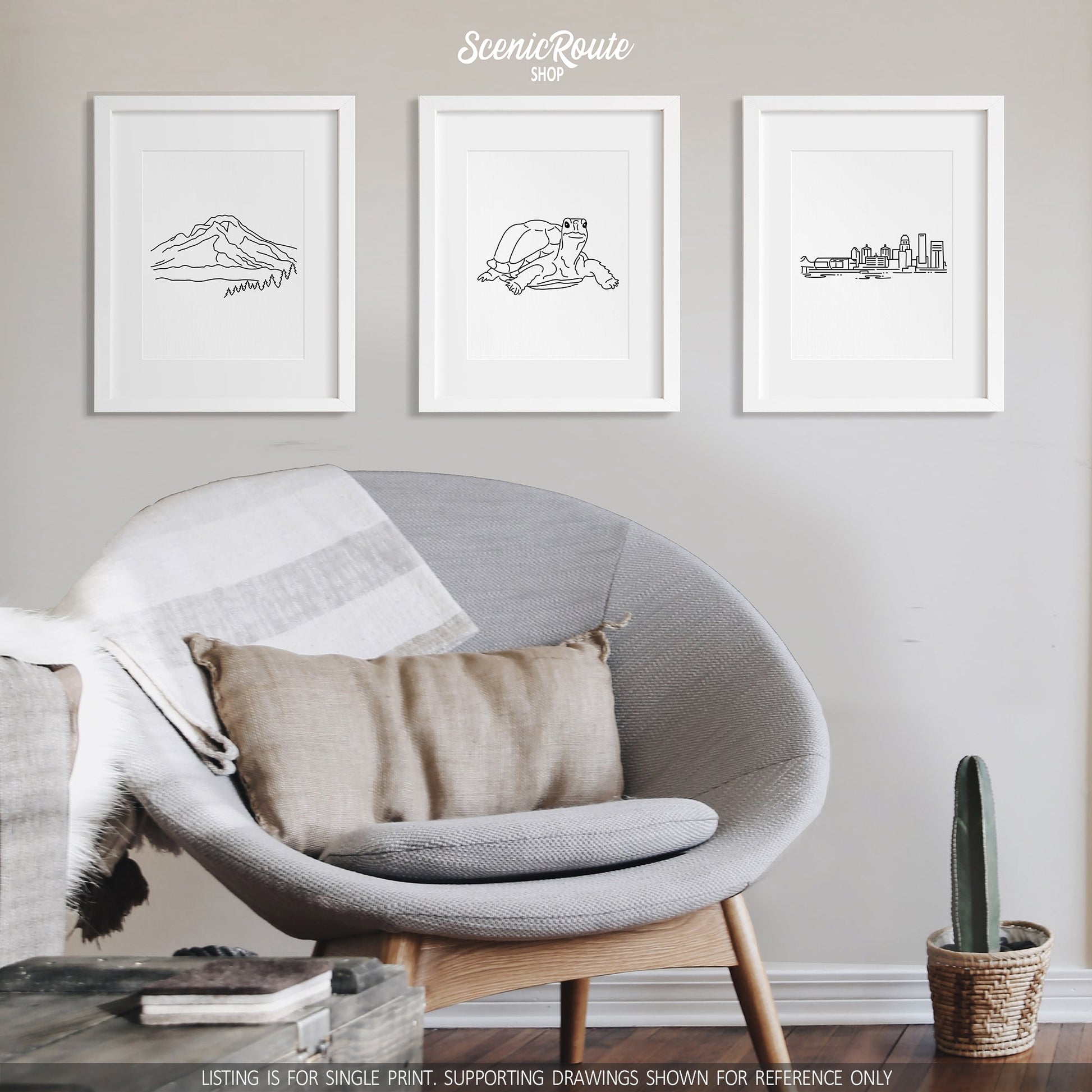 A group of three framed drawings on a gray wall above a round chair. The line art drawings include Mount Hood, a Tortoise, and the Louisville Skyline
