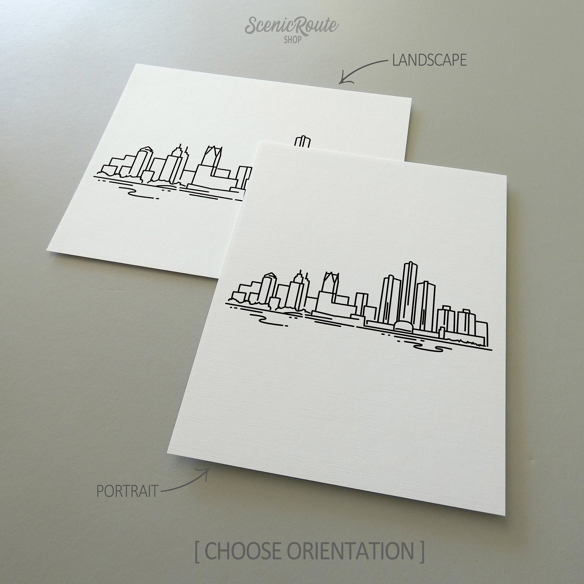 Two line art drawings of the Detroit Skyline on white linen paper with a gray background.  The pieces are shown in portrait and landscape orientation for the available art print options.