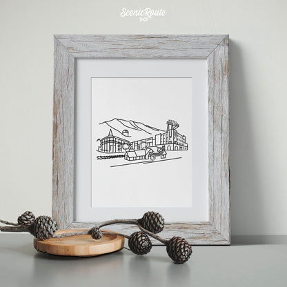 A framed line art drawing of the Flagstaff Skyline with a branch of pinecones