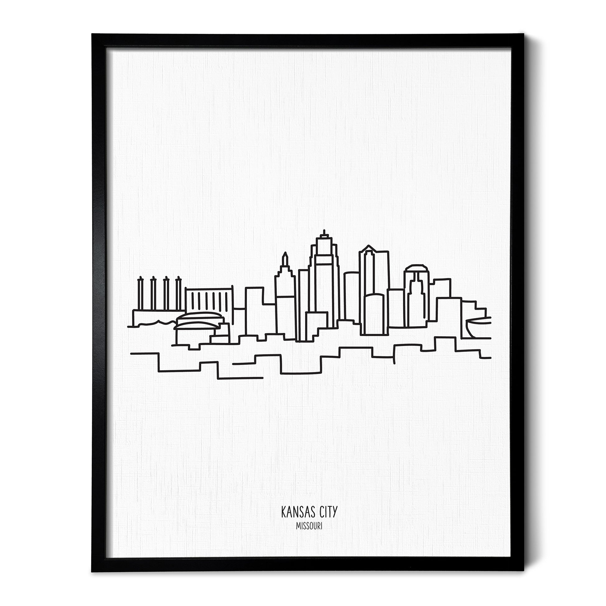 A line art drawing of the Kansas City Missouri Skyline on white linen paper in a thin black picture frame