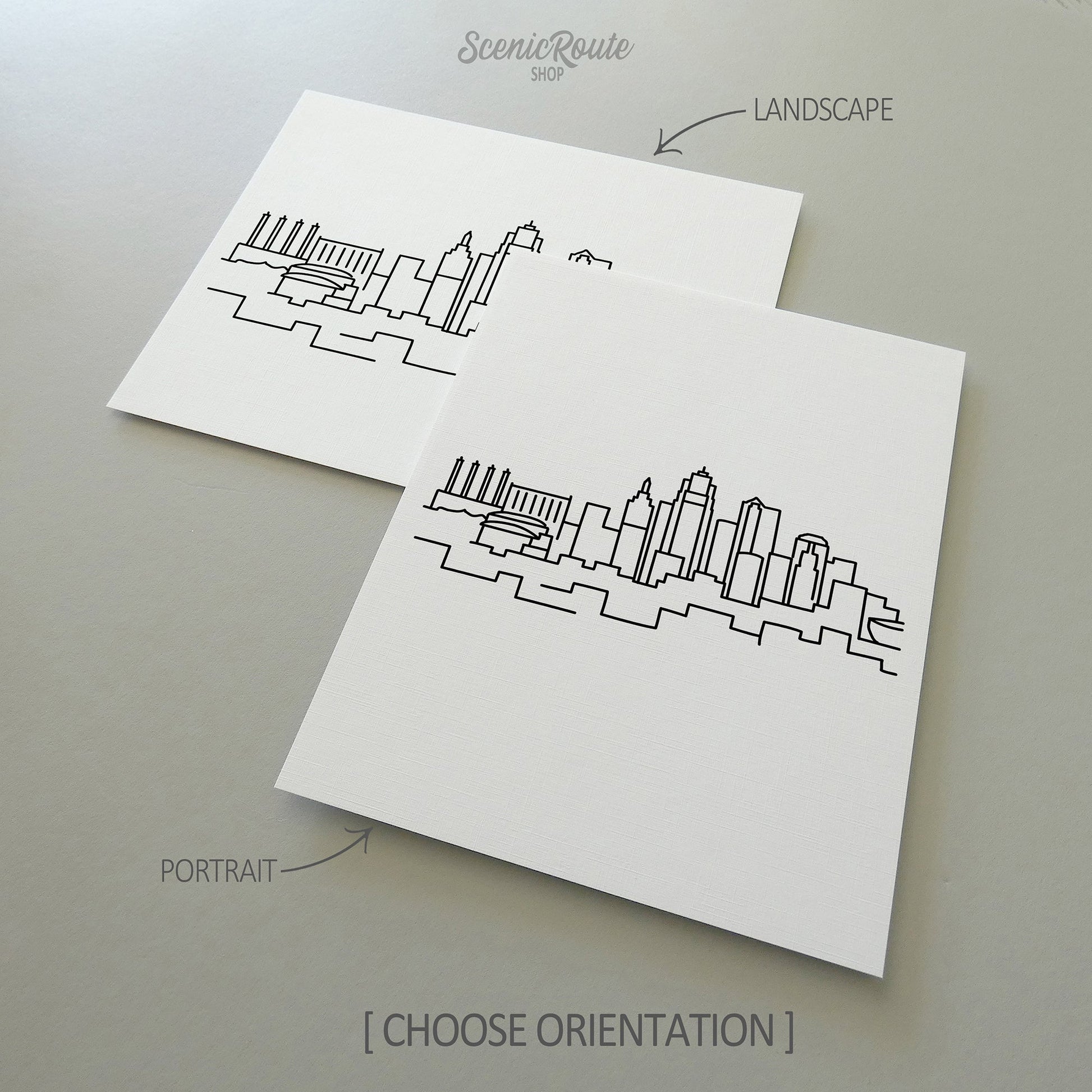 Two line art drawings of the Kansas City Skyline on white linen paper with a gray background.  The pieces are shown in portrait and landscape orientation for the available art print options.