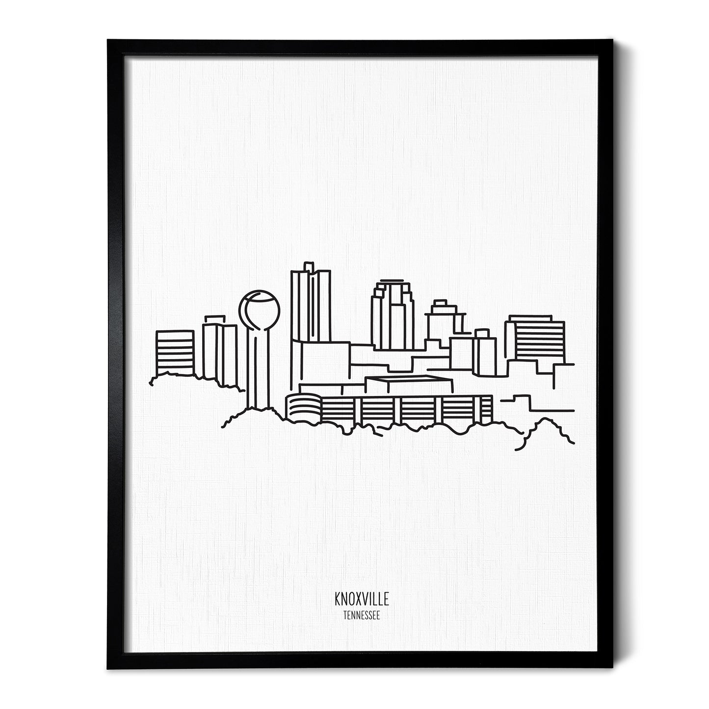 A line art drawing of the Knoxville Tennessee Skyline on white linen paper in a thin black picture frame