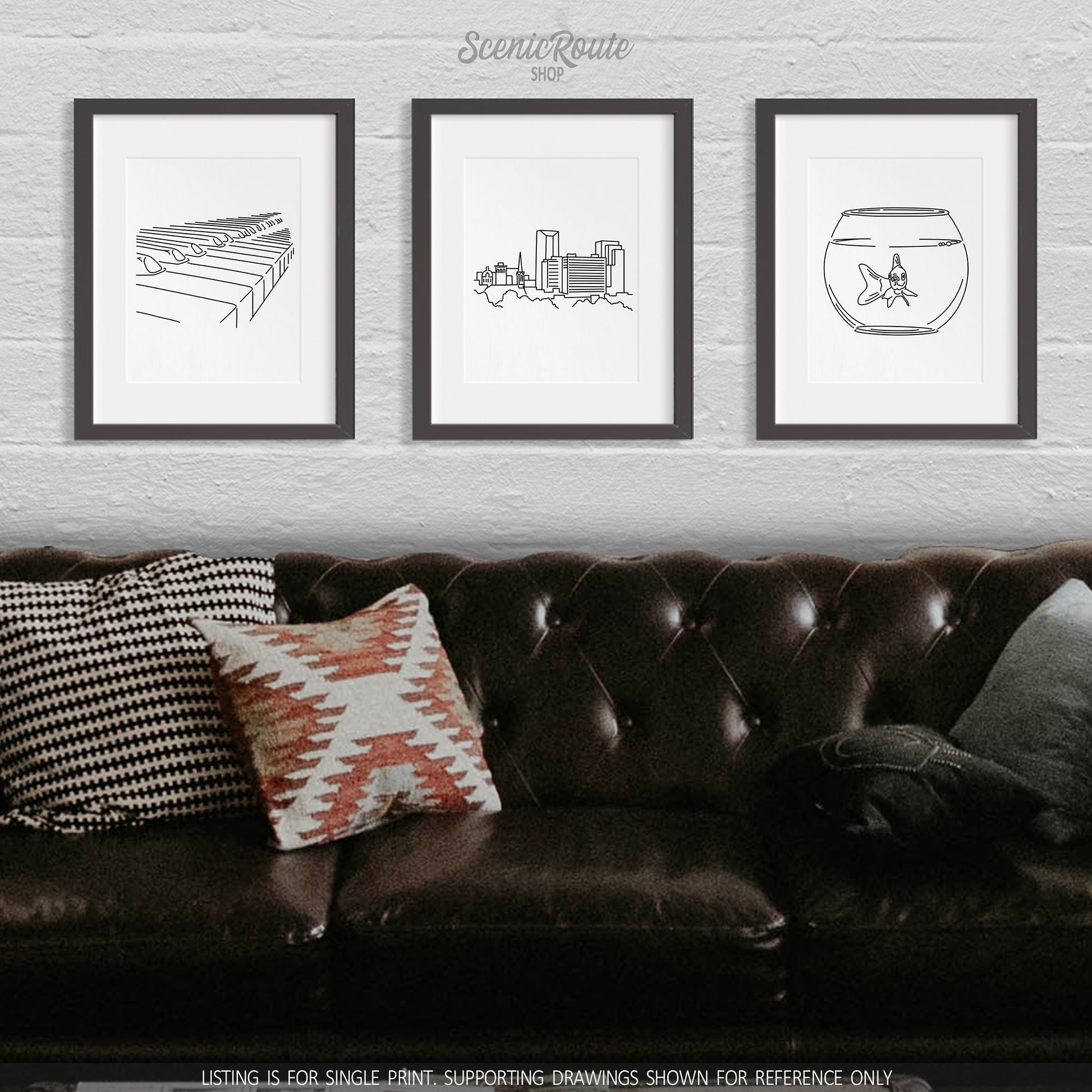 A group of three framed drawings on a wall above a couch. The line art drawings include a Piano, Lexington Skyline, and Goldfish