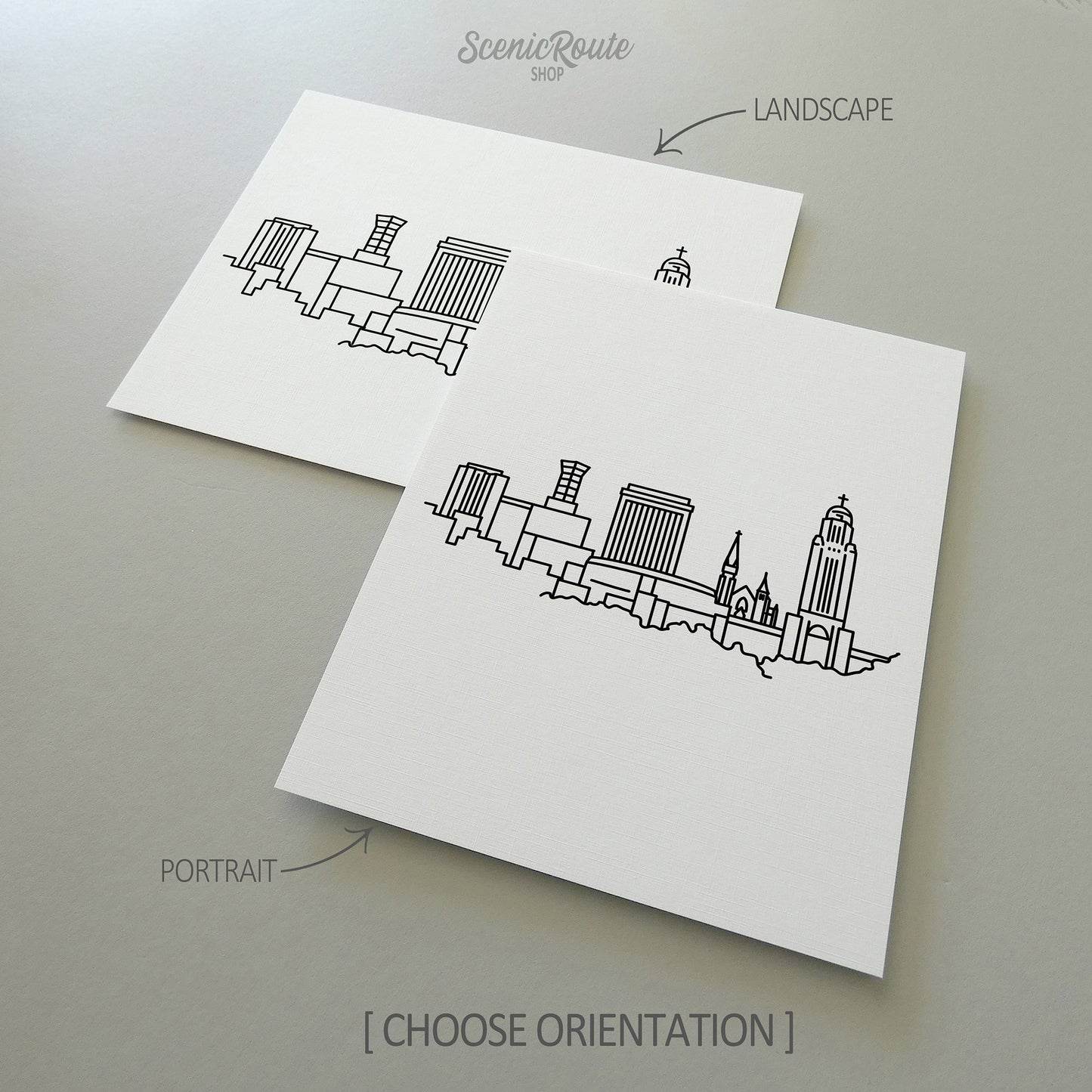 Two line art drawings of the Lincoln Skyline on white linen paper with a gray background.  The pieces are shown in portrait and landscape orientation for the available art print options.