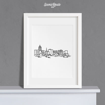 A framed line art drawing of the Madison Skyline on a mantle