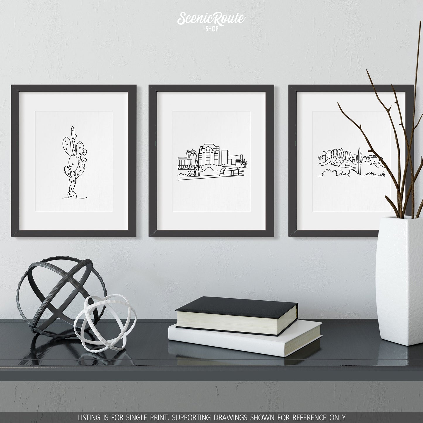 A group of three framed drawings on a wall above a dresser with books and figurines. The line art drawings include a Prickly Pear Cactus, Mesa Skyline, and the Superstition Mountains