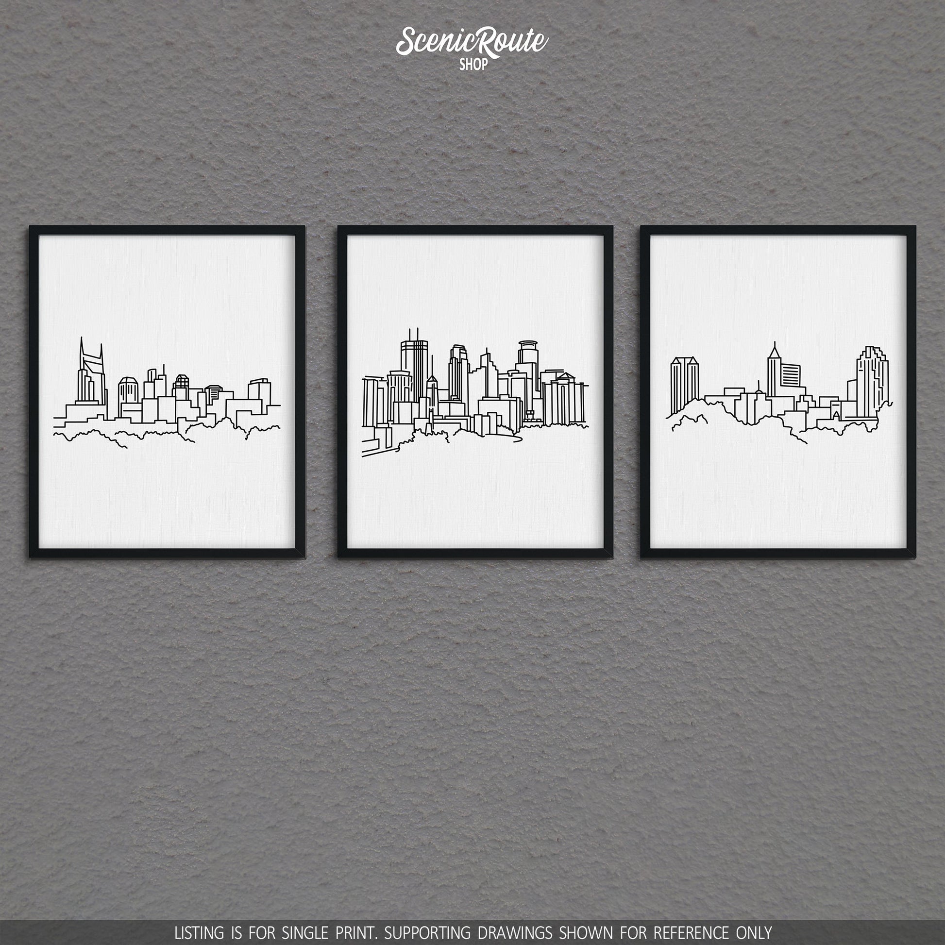 A group of three framed drawings on a gray wall. The line art drawings include the Nashville Skyline, Minneapolis Skyline, and Raleigh Skyline