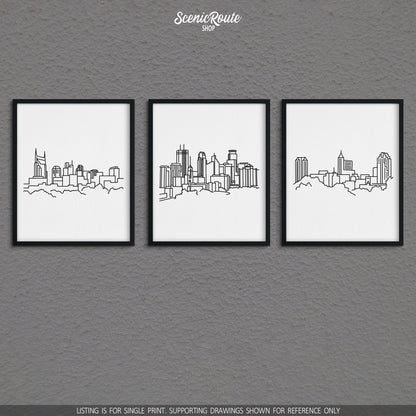 A group of three framed drawings on a gray wall. The line art drawings include the Nashville Skyline, Minneapolis Skyline, and Raleigh Skyline