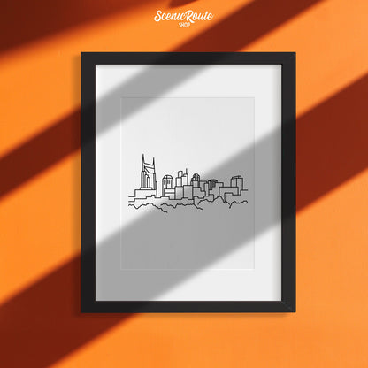 A framed line art drawing of the Nashville Skyline on an orange wall