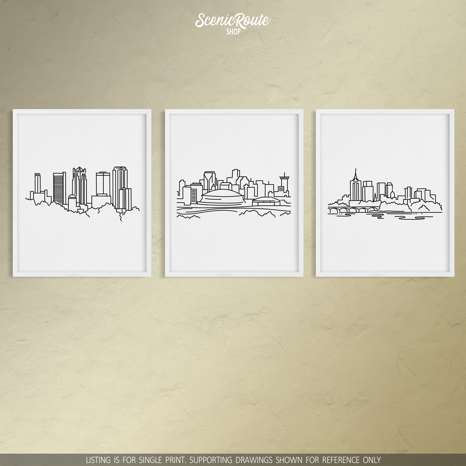 A group of three framed drawings on a tan wall. The line art drawings include the Birmingham Skyline, New Orleans Skyline, and Tulsa Skyline