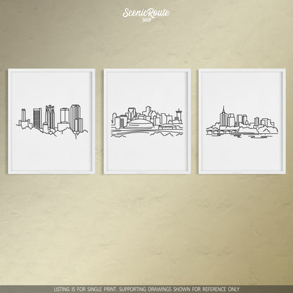 A group of three framed drawings on a tan wall. The line art drawings include the Birmingham Skyline, New Orleans Skyline, and Tulsa Skyline