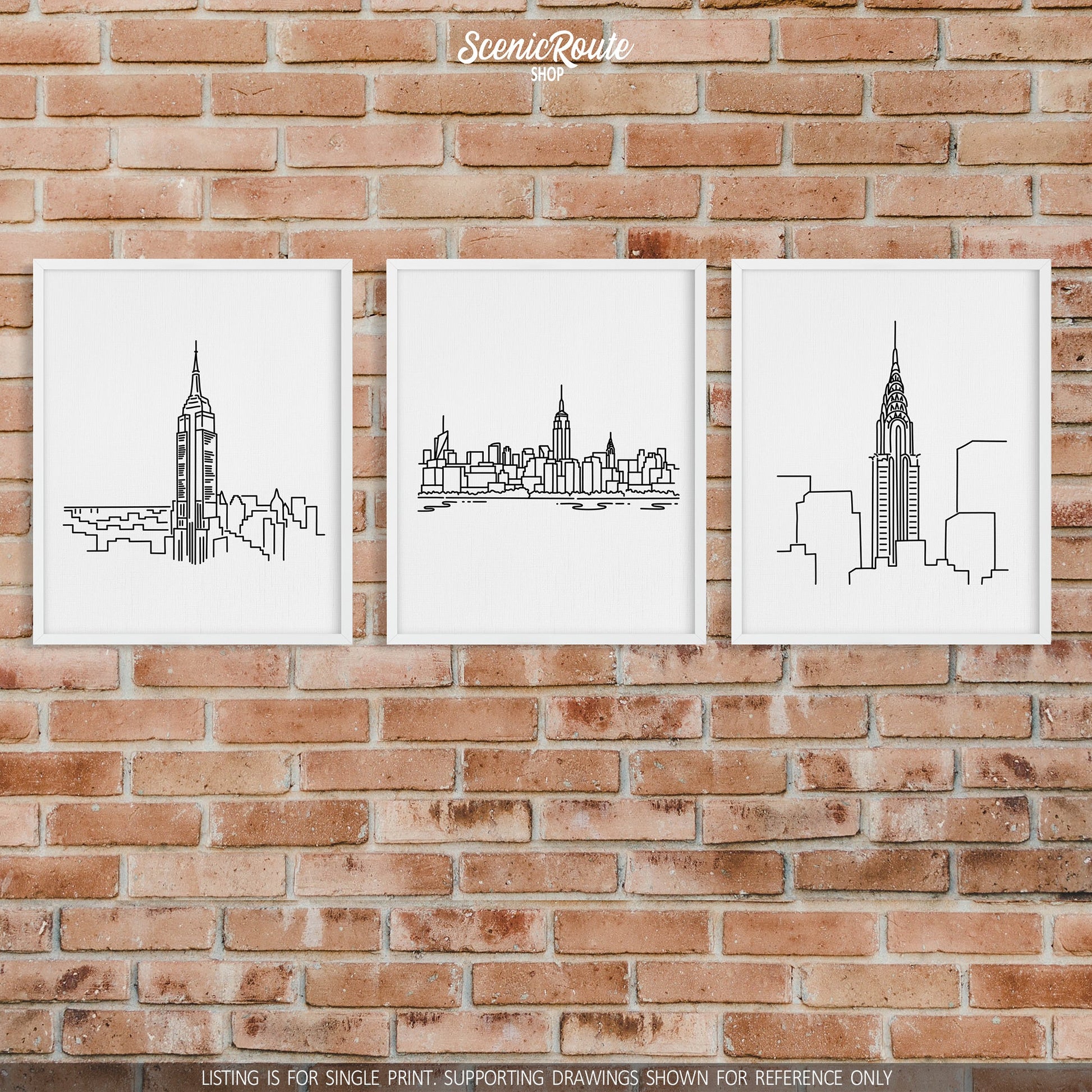 A group of three framed drawings on a brick wall. The line art drawings include the Empire State Building, New York City Skyline, and Chrysler Building