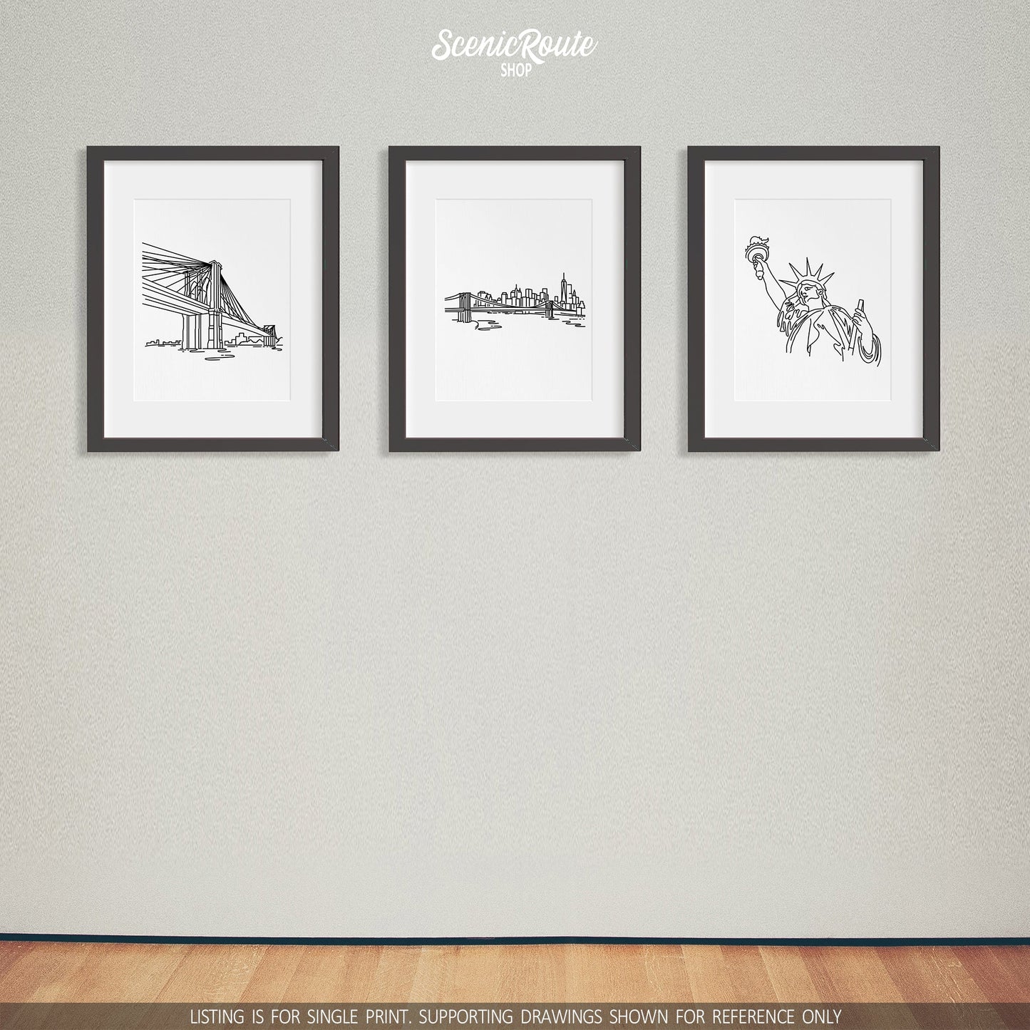 A group of three framed drawings on a gray wall. The line art drawings include the Brooklyn Bridge, New York City Skyline, and Statue of Liberty