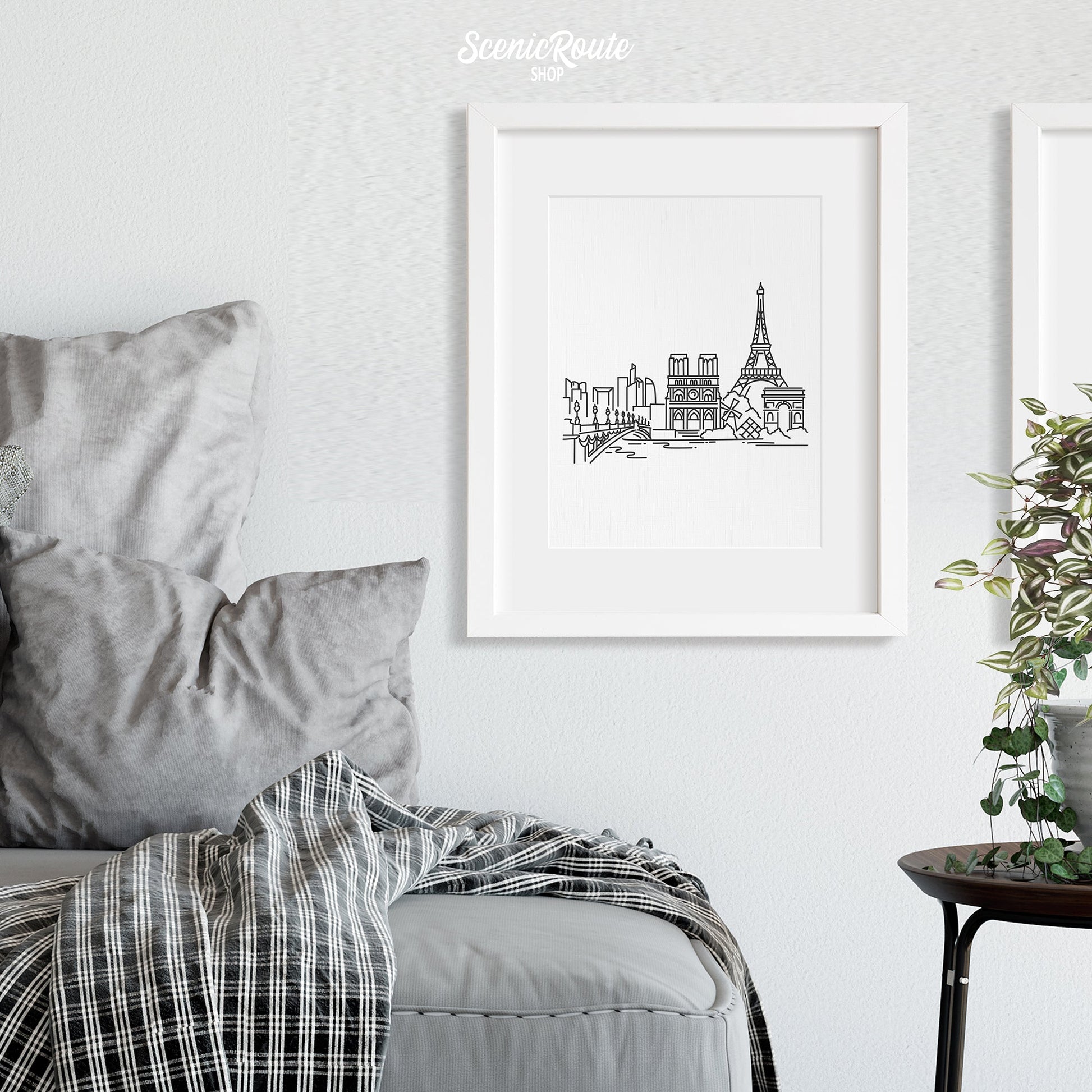 A framed line art drawing of the Paris Skyline on a white wall above a couch