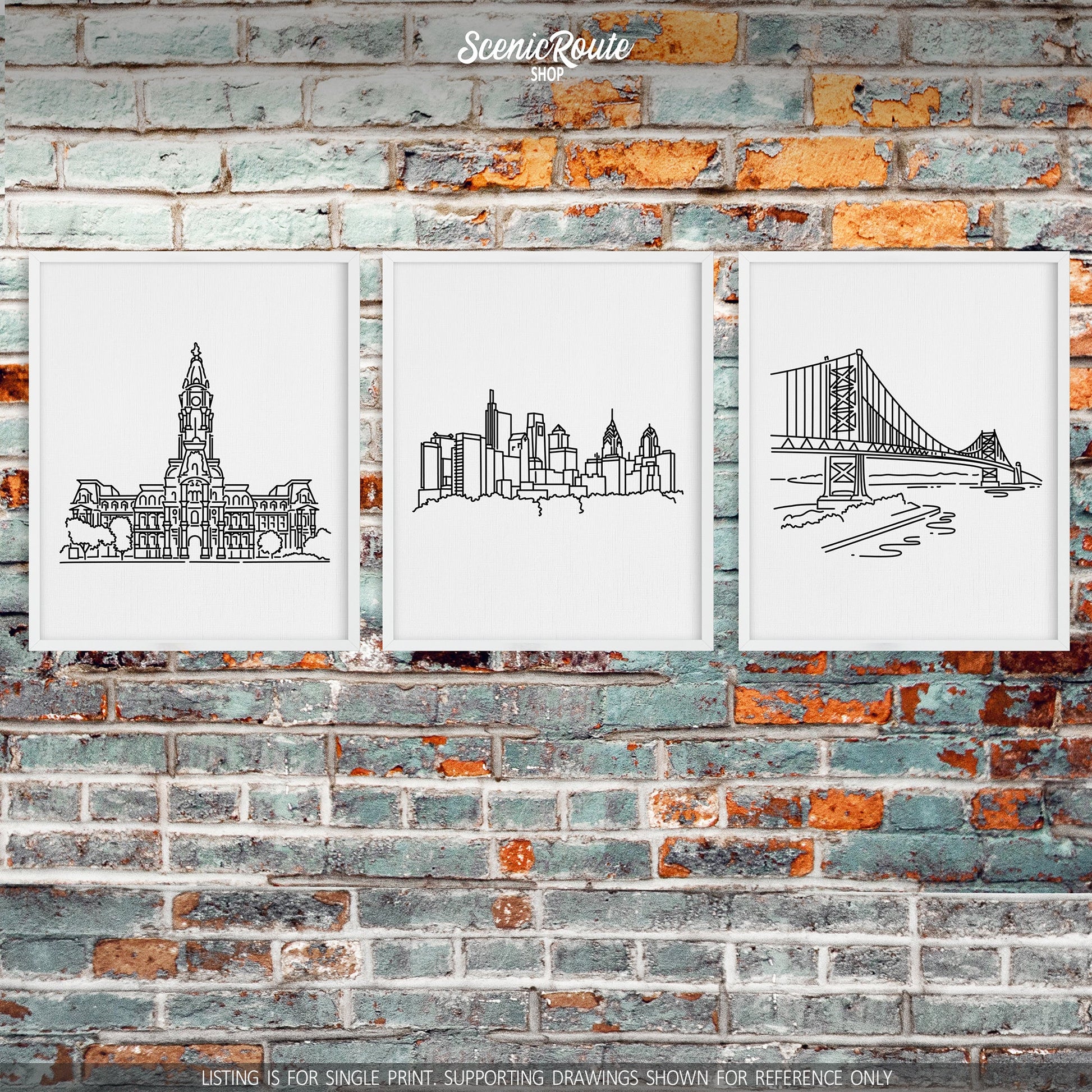 A group of three framed drawings on a brick wall. The line art drawings include the Philadelphia City Hall, Philadelphia Skyline, and Ben Franklin Bridge
