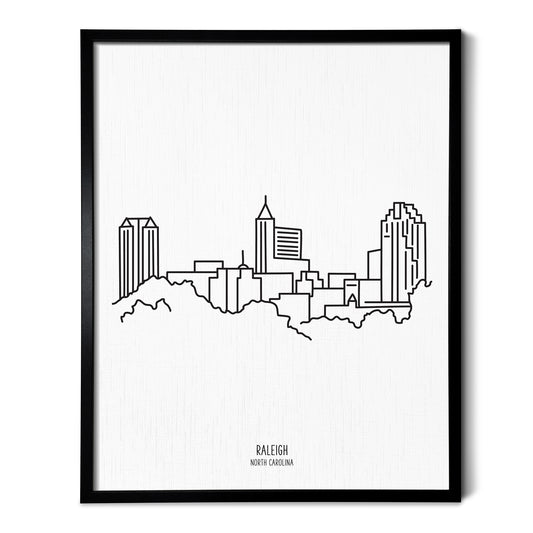 A line art drawing of the Raleigh North Carolina Skyline on white linen paper in a thin black picture frame