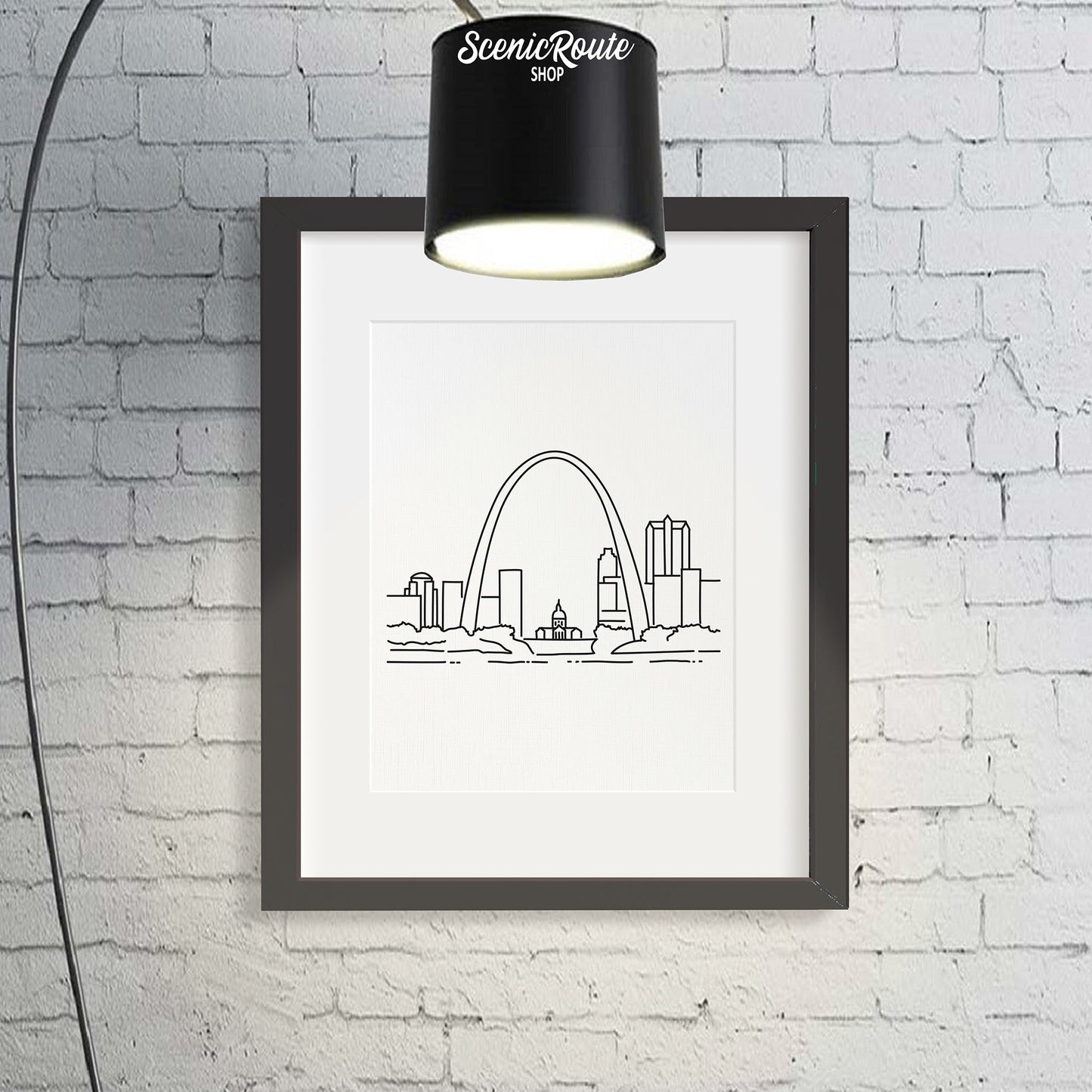 A framed line art drawing of the Saint Louis Skyline with a large lamp