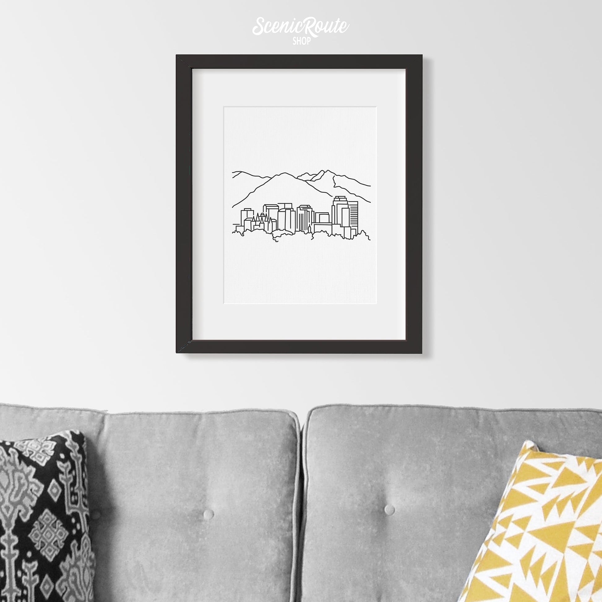 A framed line art drawing of the Salt Lake City Skyline above a couch