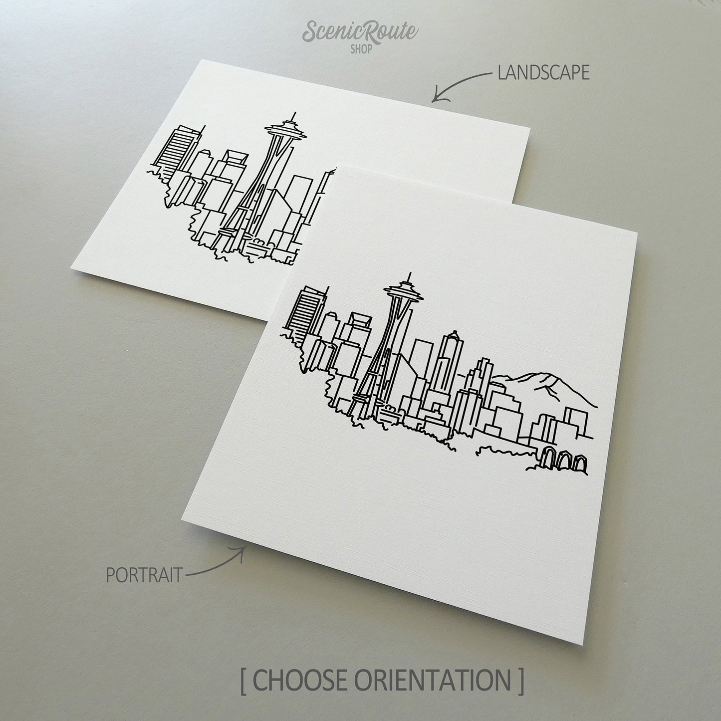 Two line art drawings of the Seattle Skyline on white linen paper with a gray background.  The pieces are shown in portrait and landscape orientation for the available art print options.