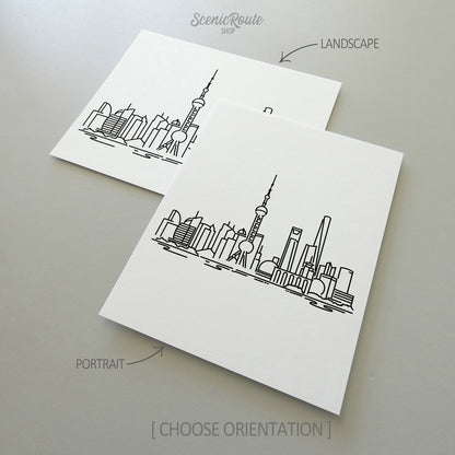Two line art drawings of the Shanghai Skyline on white linen paper with a gray background.  The pieces are shown in portrait and landscape orientation for the available art print options.