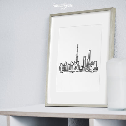 A framed line art drawing of the Shanghai Skyline on a bookcase
