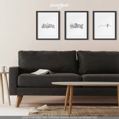 A group of three framed drawings on a wall above a couch. The line art drawings include the Montreal Skyline, Tempe Skyline, and Camelback Mountain