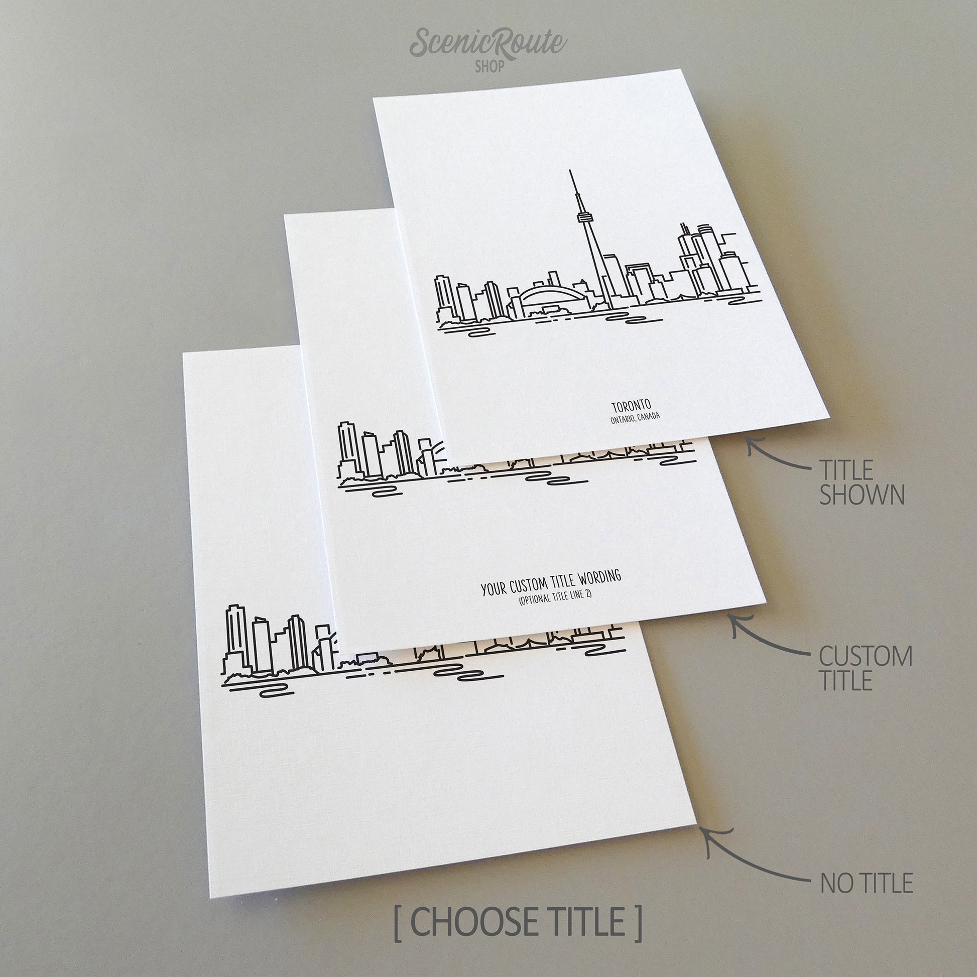 Three line art drawings of the Toronto Canada Skyline on white linen paper with a gray background. The pieces are shown with title options that can be chosen and personalized.