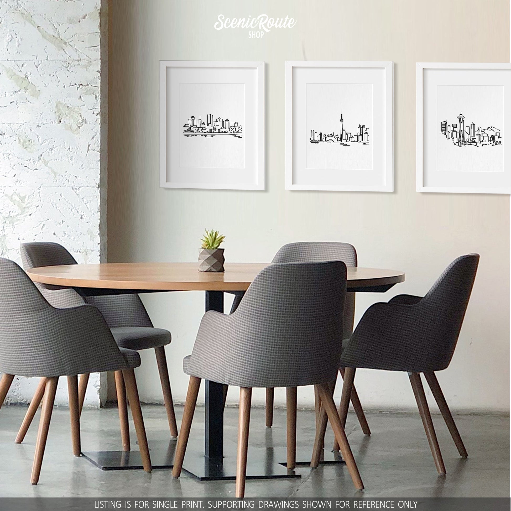 A group of three framed drawings above a dining table and chairs. The line art drawings include the Montreal Skyline, Toronto Skyline, and Seattle Skyline