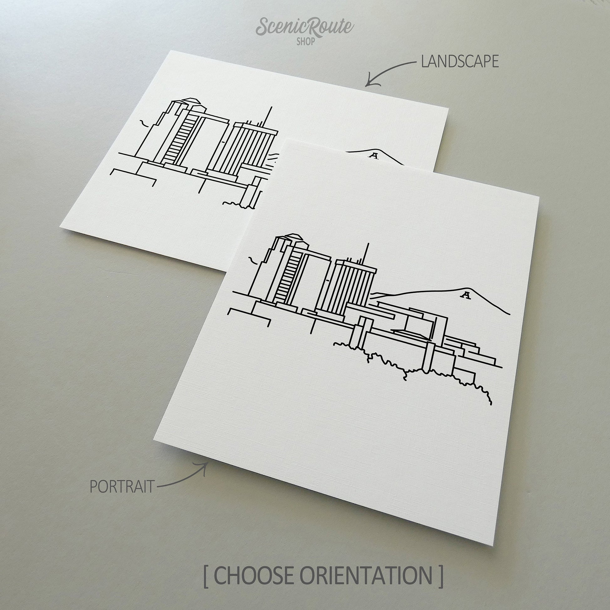 Two line art drawings of the  Tucson Skyline on white linen paper with a gray background.  The pieces are shown in portrait and landscape orientation for the available art print options.