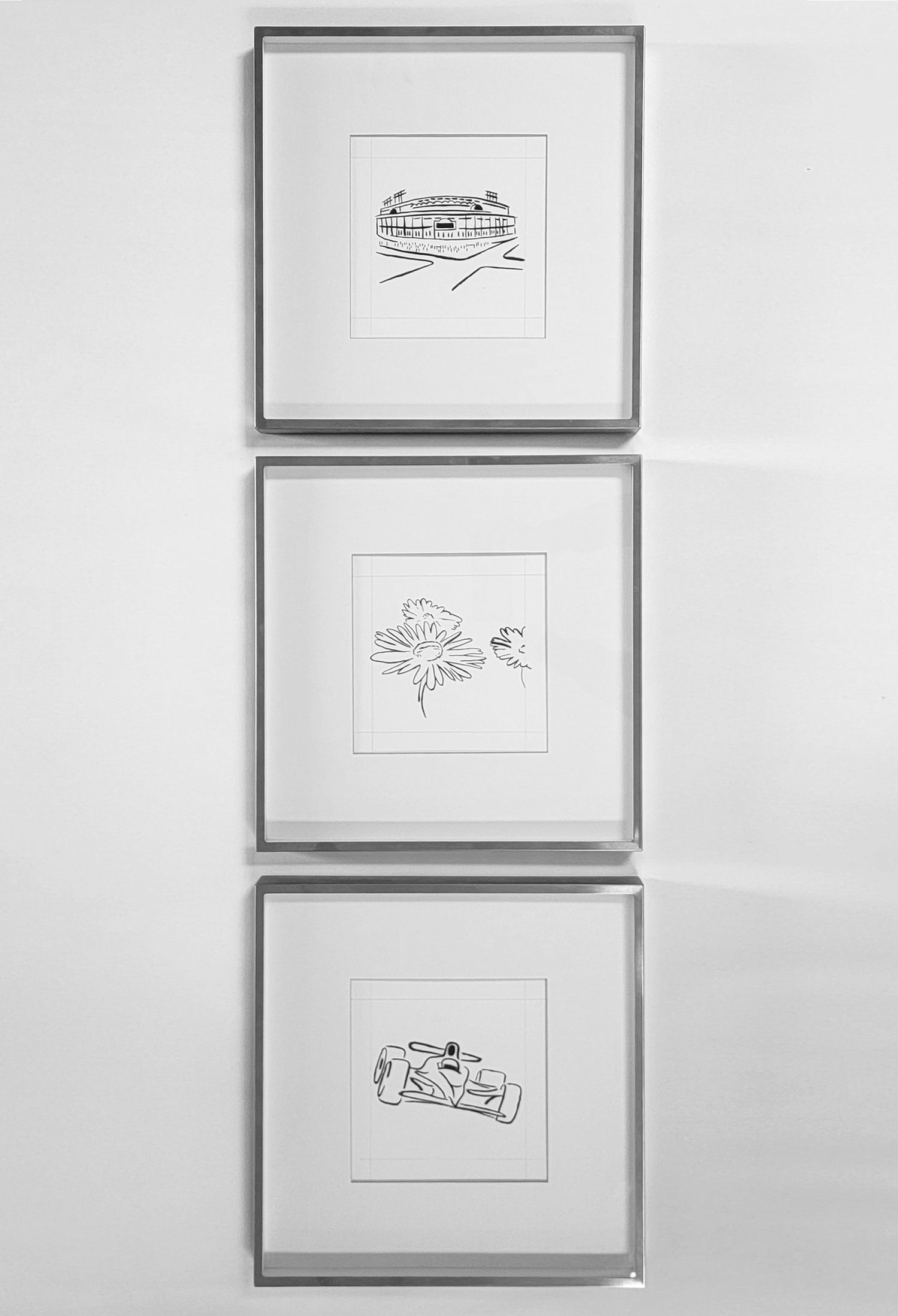 A set of three framed drawings hanging vertically on the wall